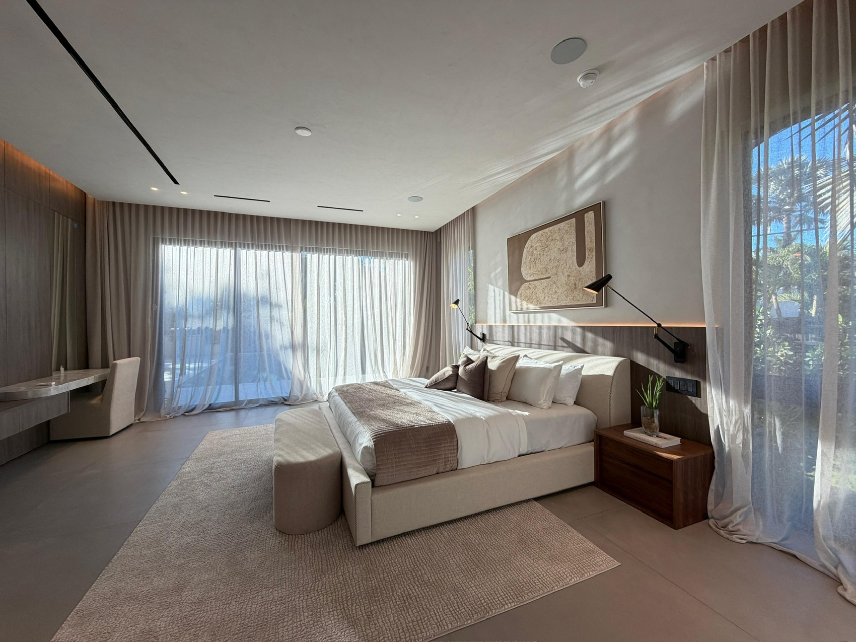 Layered drapery and sheers framing palm views in a Miami bedroom